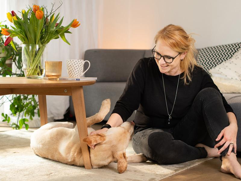 Une femme caresse un chien chez elle